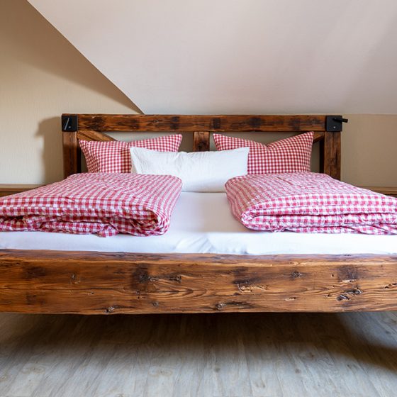 Ein tolles Doppelbett, gebaut aus massiven Balken steht in dem ersten Schlafzimmer der Ferienwohnung Tannengrün auf dem Schätzlehof in Winden im Elztal.