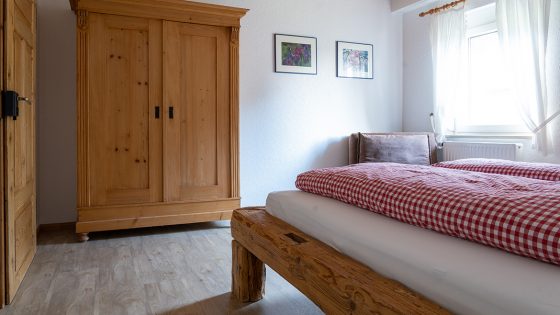 Auch im zweiten Schlafzimmer der Ferienwohnung Tannengrün steht ein antiquer Kleiderschrank, kombiniert mit einem massiven Balkenbett.