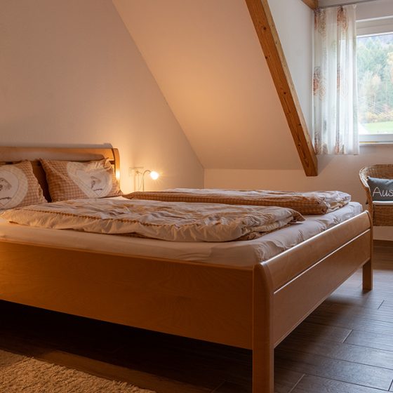 Blick auf das Doppelbett und die Sitzgelegenheit im Gästezimmer Hörnlebergblick auf dem Schätzlehof in Winden im Elztal.